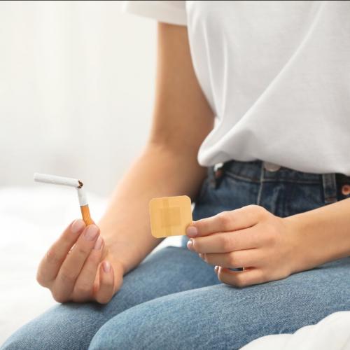 Femme qui tient une cigarette et un patch pour arrêter de fumer